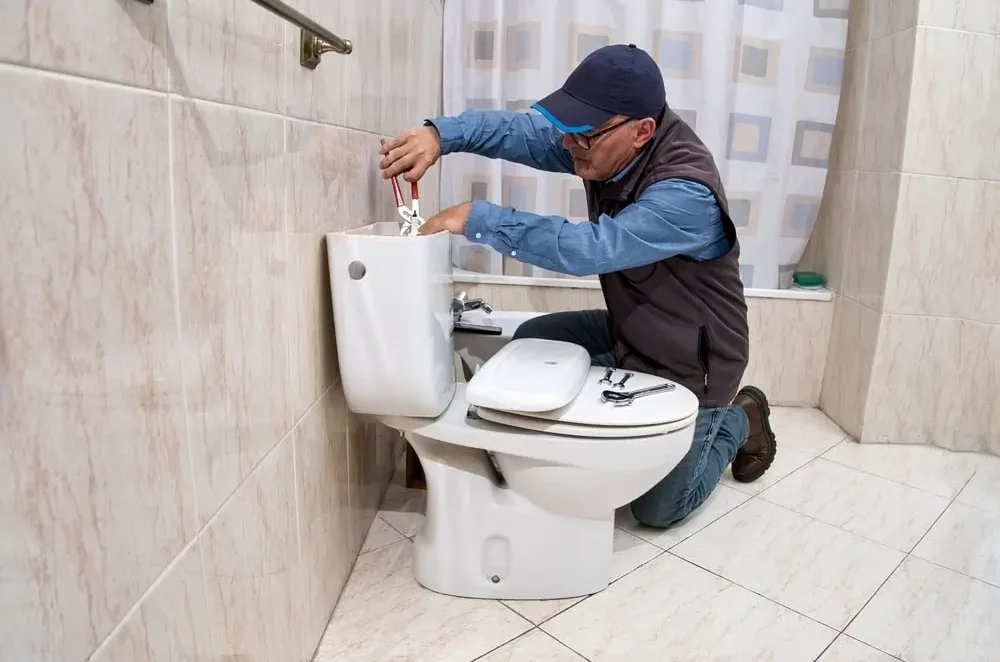 Réparation Chasse d'Eau Bruxelles Urgence 24/7 - Plombier réparant un mécanisme WC
