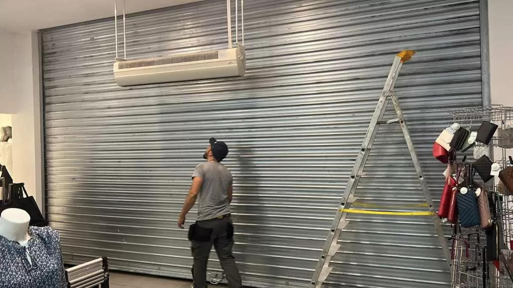 Technicien Alo Artisan BE réparant un mécanisme de rideau métallique à Bruxelles.
