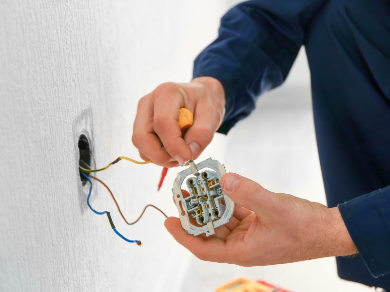 Électricien réparant une prise électrique murale à Bruxelles